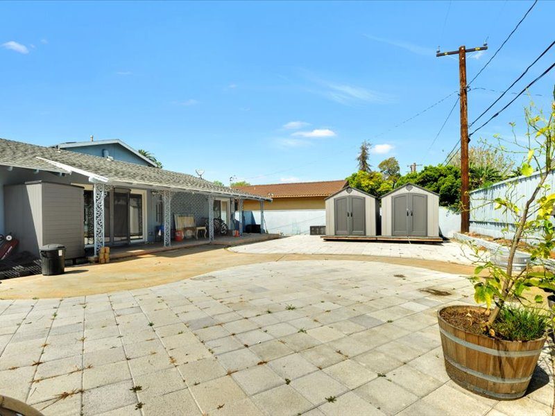 Paved rear yard with covered patio and storage
